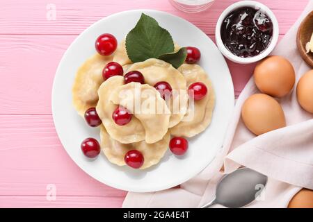 Composizione con gustosi gnocchi di ciliegia su sfondo di legno colorato Foto Stock