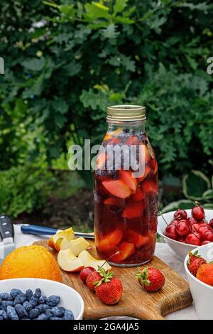 Rinfrescante limonata fatta in casa o punch sangria con agrumi e frutti di bosco biologici. Cocktail estivo con ghiaccio e succo di frutta in una bottiglia di vetro. Tast Foto Stock