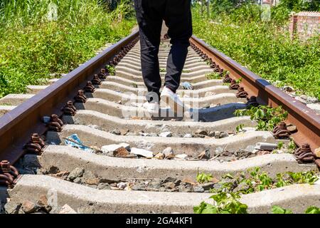 Un uomo che cammina su vecchie strade arrugginite all'aperto Foto Stock