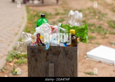 28.07.2021-Izhevsk, Russia.The cestino è traboccante con varie bottiglie di plastica Garbage.Empty e confezioni in un cestino in un parco pubblico Foto Stock