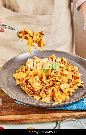 Gli spaghetti bolognesi cotti dall'apprendimento online utilizzando la ricetta del touchpad digitale, assaggiano il piatto finito Foto Stock