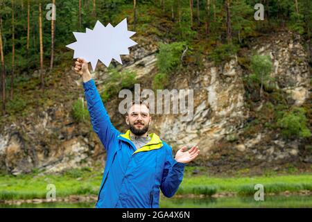 Vita su di giovane uomo bearded con bolla di parola vuota sullo sfondo del paesaggio naturale. Attenzione, senso in su, sguardo in su Foto Stock