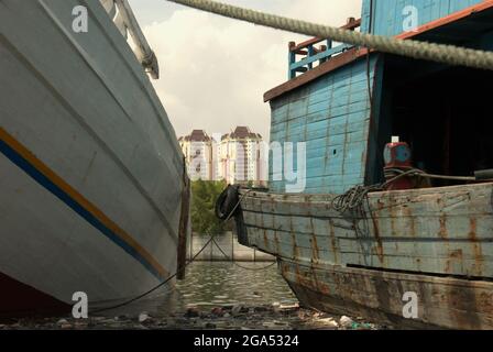 Edifici torreggianti sulla zona costiera di Giacarta sono visti attraverso le barche phinisi al porto tradizionale Sunda Kelapa a Giacarta, Indonesia. Foto Stock