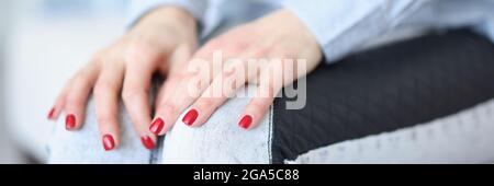 Mani femminili con manicure rossa giacente su ginocchia closeup Foto Stock