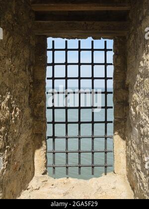 Vista sul mare attraverso i bar della fortezza Foto Stock