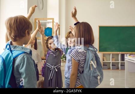 Gruppo di studenti delle scuole elementari si levano le mani e sentono lo spirito di unità. Foto Stock