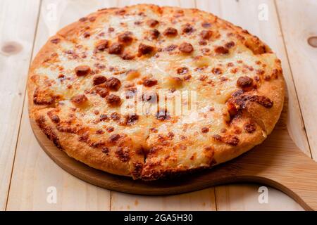 Primo piano selettivo della pizza su un vassoio di legno su un tavolo di legno. Foto Stock