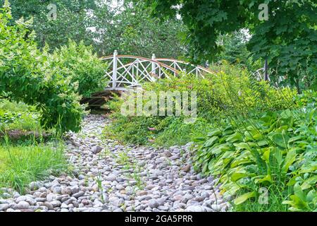 Ponte rotondo di legno sul letto asciutto di un piccolo fiume. Foto Stock