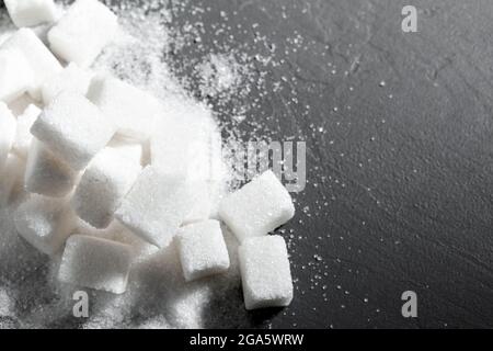 Zollette di zucchero impilati insieme contro uno sfondo nero Foto Stock