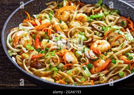 Gamberi Yaki Udon, fritti in padella di udoni con gamberetti, cavolo, funghi di castagno, cipolla primaverile, carote, mirin e salsa di soia, primo piano Foto Stock