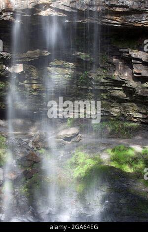 Foto a lenta esposizione scattata guardando fuori da dietro le cascate di Henrhyd, Neath, la cascata più alta del Galles meridionale, a 90 metri. Foto Stock
