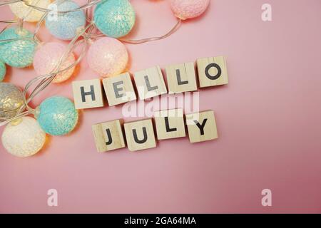 Salve lettere dell'alfabeto di luglio con decorazione a sfere di cotone a LED su sfondo rosa Foto Stock