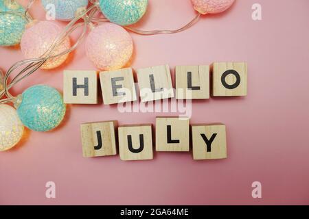 Salve lettere dell'alfabeto di luglio con decorazione a sfere di cotone a LED su sfondo rosa Foto Stock