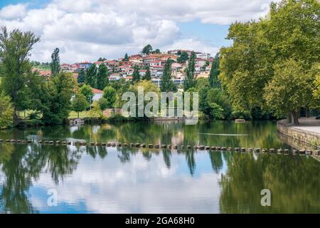 Fiume Támega, acqua calma, luogo di svago, passo di pietra sul fiume. Chavez paesaggio urbano con alberi frondosi. Relax paesaggio. Foto Stock