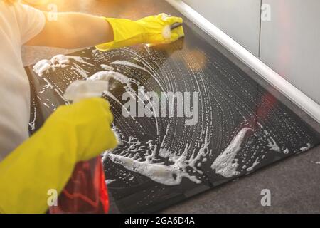 Persona pulizia fornello elettrico in cucina moderna foto Foto Stock