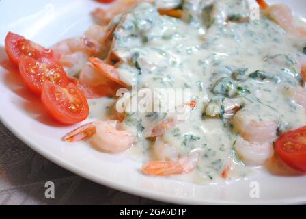 Gamberi con spinaci e parmigiano in salsa di panna da vicino su un piatto su un tavolo. Foto Stock