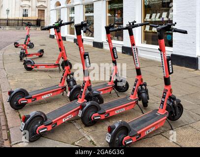 CAMBRIDGE INGHILTERRA UNA LINEA DI SCOOTER ROSA VOI E FUORI DALL'EDIFICIO DELLA STAMPA DELL'UNIVERSITÀ DI CAMBRIDGE IN TRINITY STREET Foto Stock