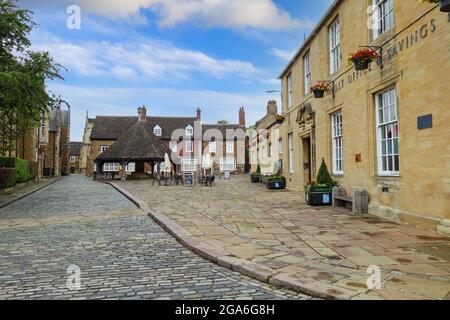 La Buttercross, la croce del burro o la croce del mercato e l'ex ufficio postale e banca di risparmio a Oakham, la città della contea di Rutland, Inghilterra, Regno Unito Foto Stock