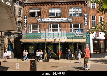 Orford Place Norwich centro città Paddy Power bookmaker con rudeboy studio e un Tattoo e piercing negozio con persone in fila all'aperto per piercing. Foto Stock