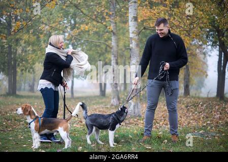 i proprietari di animali domestici con husky siberiano e cani da aquila si sono bene a visitare il parco cittadino una mattina d'autunno Foto Stock