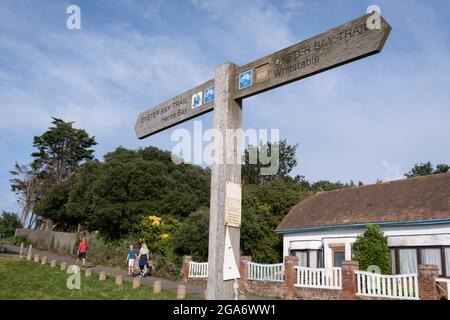 Un cartello per il 'Oyster Bay Trail' punta alla rotta est-ovest tra lungo la costa nord del Kent, un tema per i frutti di mare coltivati storicamente locali, il 25 luglio 2021, a Whitstable, Kent, Inghilterra. L'Oyster Bay Trail è un percorso di 6.7 km a piedi e in bicicletta, un'estensione del famoso Viking Coastal Trail che collega Reculver Country Park a Bishopstone, Herne Bay e Swalleffe. Foto Stock