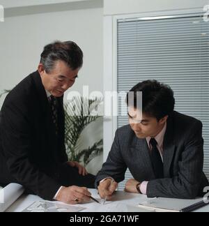 Dirigenti aziendali alla scrivania dell'ufficio, che discutono dei piani. Foto Stock