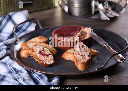 Delicato pato di pollo con purè di mirtilli spalmato su fette di baguette tostate. Cibo di stile country. Foto Stock