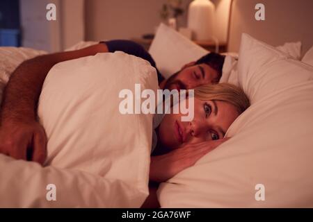 Coppia con Donna sdraiata in letto sveglio di notte con Insomnia Foto Stock