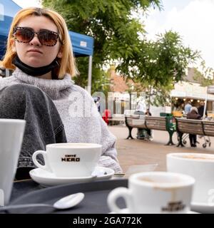 Epsom Surrey London, luglio 29 2021, Young Woman da sola seduto fuori Cafe Nero Coffee Shop in UNA Piazza del mercato Foto Stock