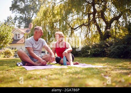 Coppia senior a casa in giardino indossare abbigliamento fitness rilassarsi dopo una lezione di yoga all'aperto Foto Stock
