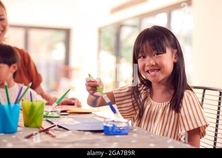 Madre asiatica con i bambini che hanno divertimento con i bambini che fanno l'artigianato sul tavolo a casa Foto Stock