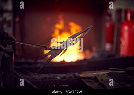 Primo piano di Male Blacksmith metallo di raffreddamento in acqua dopo l'estrazione di Forge Foto Stock