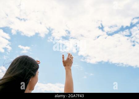 La ragazza alza le mani verso il cielo. Pregare Dio. Primo piano Foto Stock