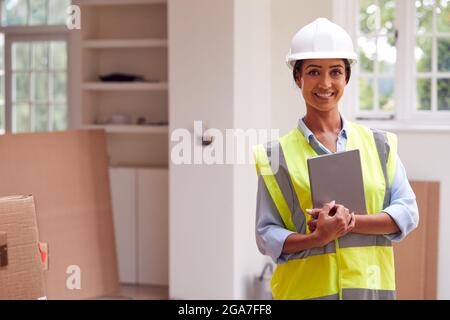 Ritratto di Surveyor da costruzione femminile che indossa un casco rigido con un tablet digitale guardando New Property Foto Stock