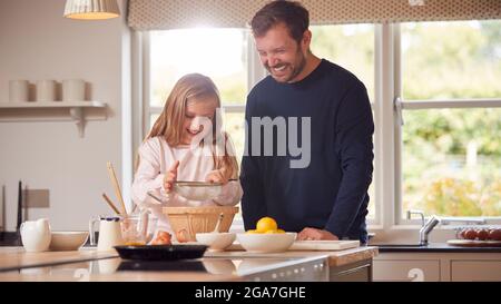 Padre e figlia che indossano Pajama che fanno i pancake in cucina a casa insieme Foto Stock