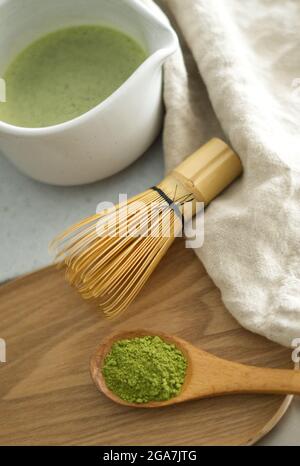 Mescolando la polvere verde di matcha giapponese in un bianco chawan di ceramica con legno di bambù marrone chasen Foto Stock