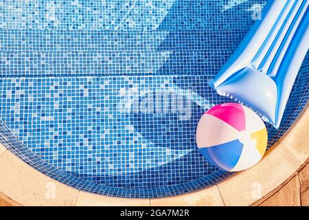 Tiro di aria-letto gonfiabile e palla da spiaggia galleggiante in piscina all'aperto Foto Stock