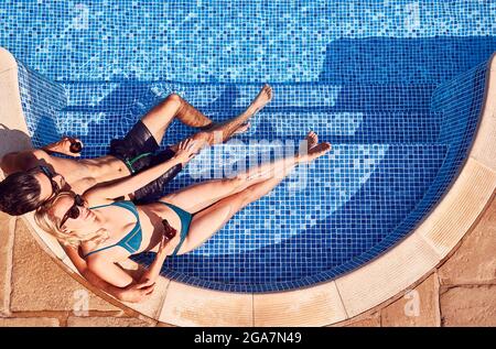 Foto in alto di coppia in costume da bagno relax in piscina all'aperto bere birra Foto Stock
