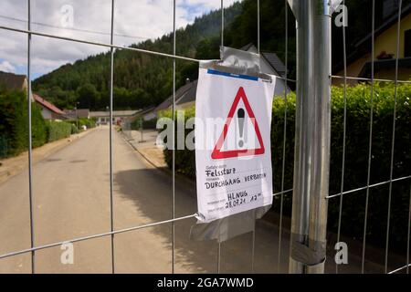 29 luglio 2021, Renania-Palatinato, Ahrbrück: In una valle laterale del fiume Ahr, c'è una recinzione con l'avviso 'Felssturz, Durchgang verboten'. Lì, una roccia del peso di circa 500 tonnellate minaccia di cadere sulle case già colpite dal disastro alluvionale. Foto: Thomas Frey/dpa Foto Stock