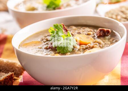 Zuppa di lenticchie con pezzi di collo di maiale affumicato, carote, patate e coriandolo. Cucina tradizionale slovacca, ceca o dell'Europa orientale. Foto Stock