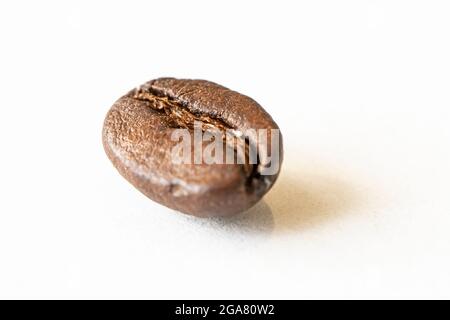 Chicchi di caffè su sfondo bianco. Una macro foto di chicchi di caffè marrone fritti sul tavolo bianco. Foto Stock