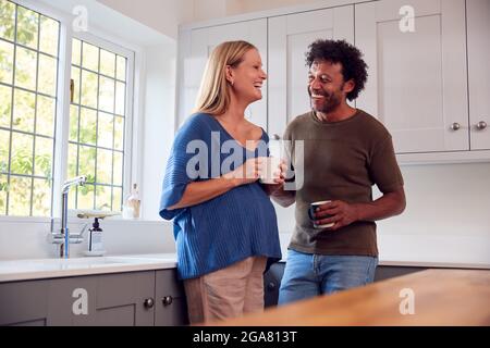 Coppia con la moglie incinta in cucina che parla e beve il caffè insieme Foto Stock