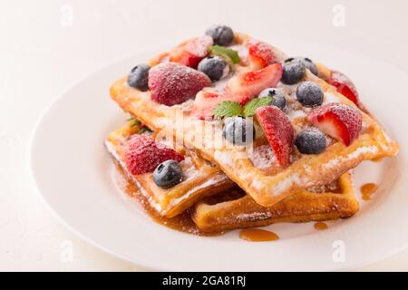 Waffle belgi con fragole, mirtilli e sciroppo, sana colazione fatta in casa, focalizzazione selettiva Foto Stock