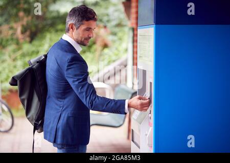 Businessman pendolaring fare Contactless pagamento per il biglietto del treno alla stazione macchina con carta Foto Stock