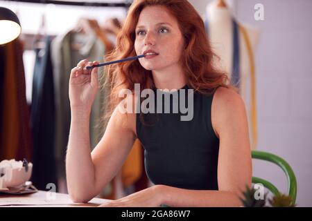 Pensieroso studente femminile o imprenditore che lavora in disegni di Fashion Sketching in Studio Foto Stock