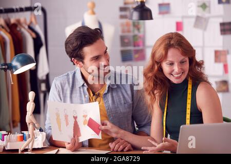 Studenti di sesso maschile e femminile o Business Owners che lavorano insieme su disegni in Studio di Moda Foto Stock