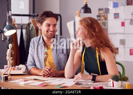 Studenti di sesso maschile e femminile o Business Owners che lavorano insieme su disegni in Studio di Moda Foto Stock