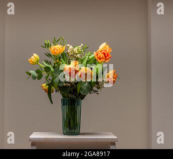 Un bouquet di pesche e rose color arancio su un piccolo tavolo. Foto Stock