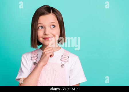 Foto di mentalità sognante giovane ragazza sguardo vuoto spazio tenere mano mento isolato su sfondo colore teal Foto Stock