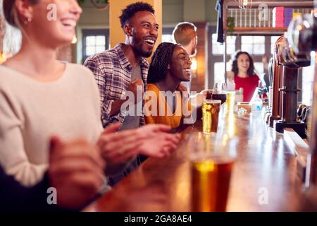 Gruppo di clienti entusiasti in Sports Bar Watching Sporting Event on Television Foto Stock